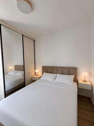 a bedroom with a large white bed and two lamps at Stan 11 in Đenovići