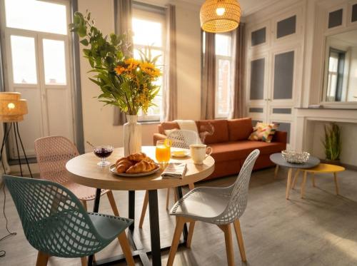 a living room with a table and chairs and a couch at Beau 2 pièces climatisé, beaux volumes et lumineux - toutes commodités - Lille Gares direct en 30 minutes in Tourcoing