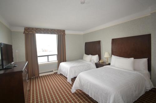 a hotel room with two beds and a window at Prince Arthur Waterfront Hotel & Suites in Thunder Bay