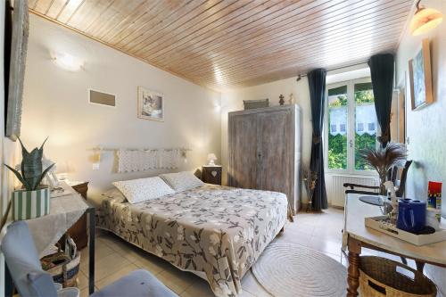 a bedroom with a bed and a table and a window at Chambres D'hôtes Le Peux in Saint-Pierre-le-Vieux