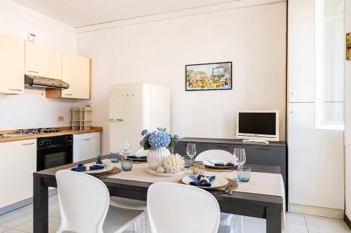 a kitchen with a dining room table with white chairs at Harbour View Apartment - Elite Grado Centro in Grado