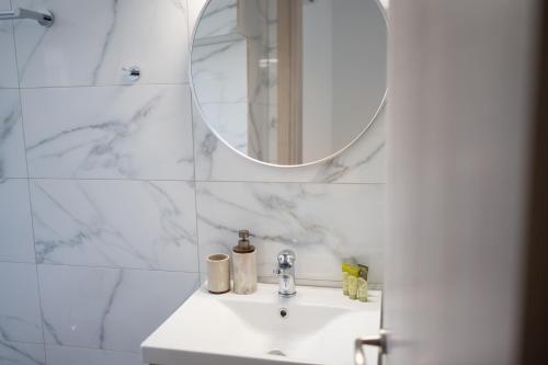a white bathroom with a sink and a mirror at Studios Kerasioti in Pefki