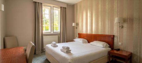 a hotel room with a bed with towels on it at Logis Hôtel Du Château - Combourg, Proche Saint-Malo in Combourg