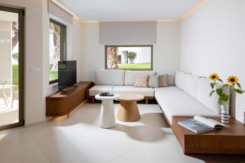 a living room with a white couch and a tv at Agapi Beach Resort Premium All Inclusive in Amoudara Herakliou