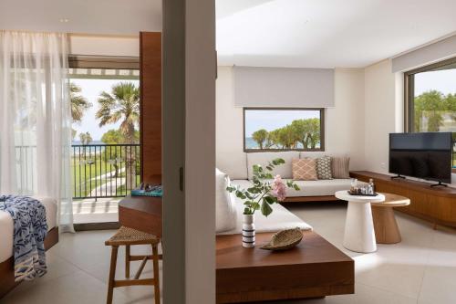 a living room with a couch and a tv at Agapi Beach Resort Premium All Inclusive in Amoudara Herakliou