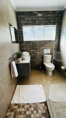 a bathroom with a toilet and a sink and a window at Die Kothuis in Wolseley