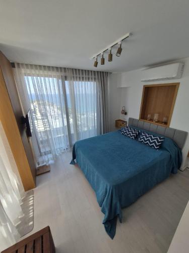a bedroom with a blue bed and a large window at Helis Bodrum Residence in Milas