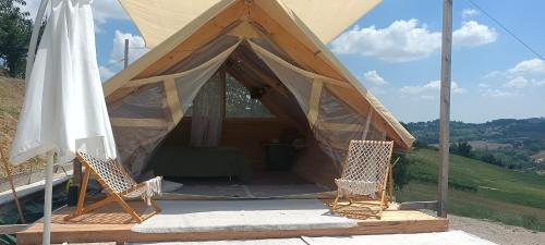 a tent with two chairs and an umbrella at Glamping Casacocco' in San Ginesio