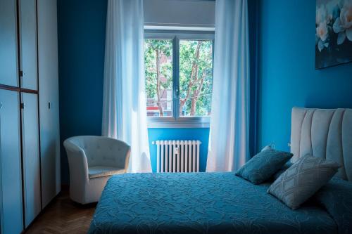 a blue bedroom with a bed and a chair and a window at El Prestinée Box auto gratuito in Milan