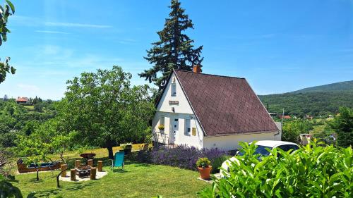 a small white house with a tree in the yard at Hillside Cottage in Pécs