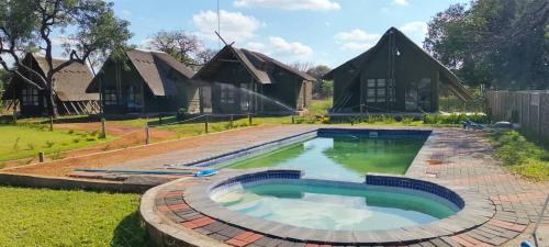 a swimming pool in a yard with houses at Tsetsebjwe Lodge in Baines Drift
