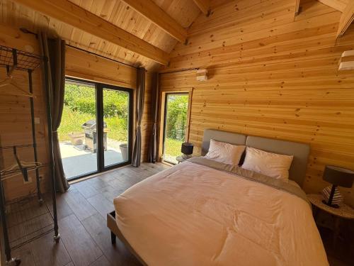 a bedroom with a bed in a log cabin at Chalet en bois indépendant, terrasse et accès piscine in Montret