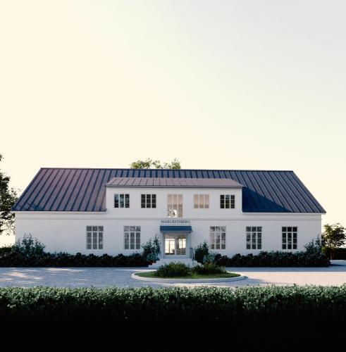 a large white house with a black roof at Margretes Badhotell in Strandbaden