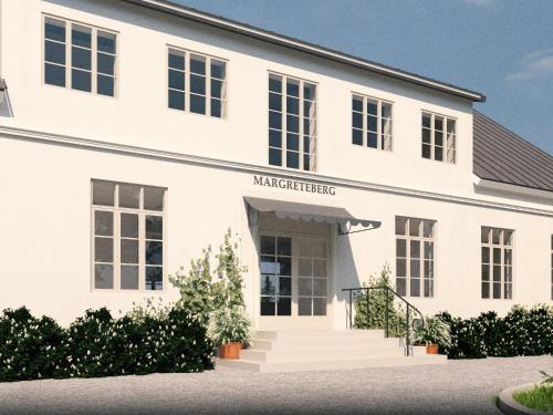 a white building with the entrance to amarketride at Margretes Badhotell in Strandbaden