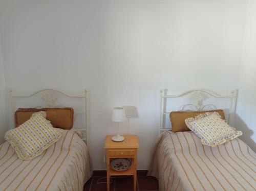 two twin beds in a room with a night stand at Typical Alentejo House in Mora