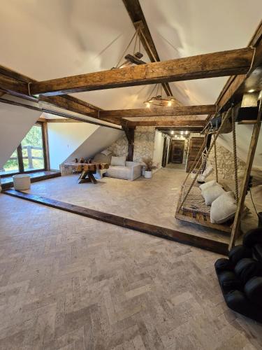 an attic room with a wooden floor and a table at Apartament-SŁOVIAŃSKI ZAKĄTEK in Nowakowo
