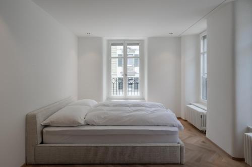 a bed in a white room with a window at ODA Suites - self check-in apartments, old town in Lucerne