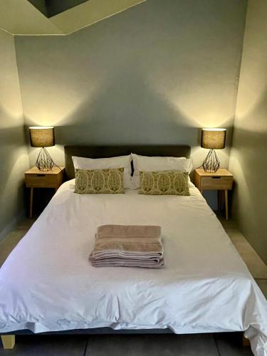 a bedroom with a white bed with two lamps at The Kite Cottage in Langebaan