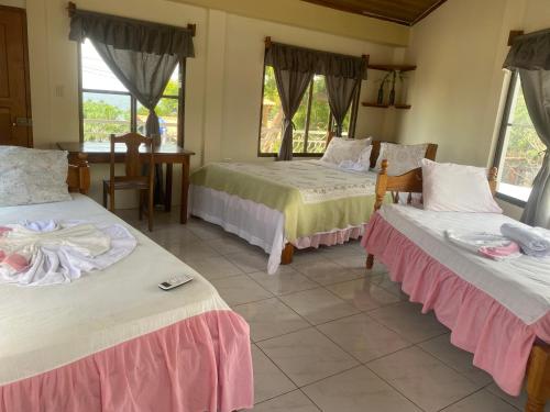 a room with three beds and a table and windows at Hotel Restaurante Los Cocos in Santa Cruz