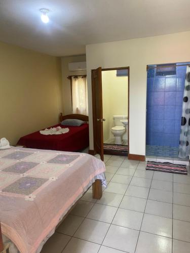 a bedroom with a bed and a bathroom with a toilet at Hotel Restaurante Los Cocos in Santa Cruz