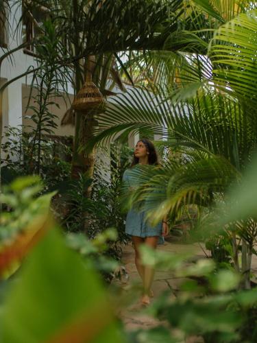 a woman walking through a garden with plants at Tamu Tamu Boutique Hotel in Pwani Mchangani