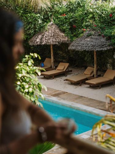 a group of lounge chairs and umbrellas next to a swimming pool at Tamu Tamu Boutique Hotel in Pwani Mchangani
