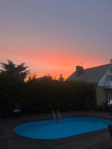 a swimming pool with a sunset in the background at Saules namu kambariukas in Palanga