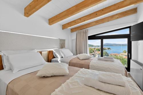 two beds in a room with a large window at September15 Boutique Suites - Nikiana in Nikiana