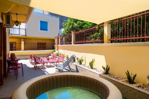 a patio with a swimming pool and tables and chairs at Pinotsi Rooms Village Symi in Symi