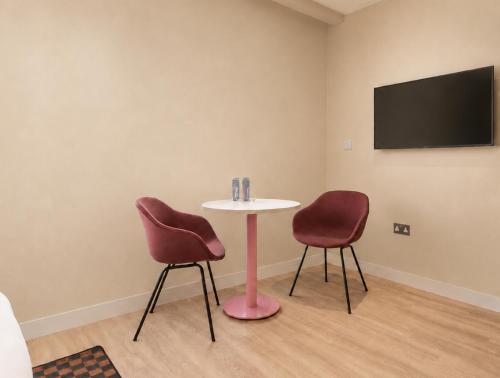 a room with two chairs and a table and a tv at Numa Brighton Pavilion in Brighton & Hove