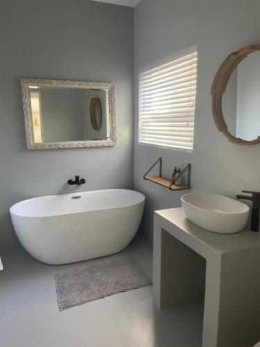 a bathroom with a large white tub and a mirror at The Kite Manor in Langebaan