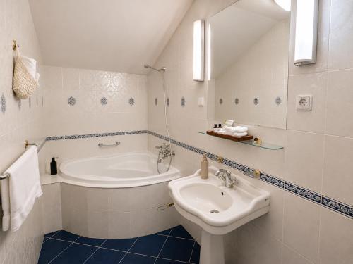 a white bathroom with a sink and a bath tub at Park Hotel Tartuf in Beladice