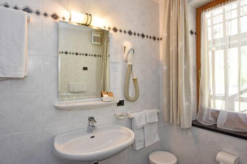 a white bathroom with a sink and a mirror at Hotel Malga Passerella in Moena