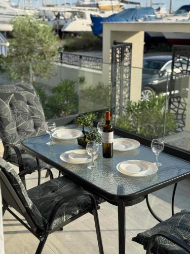 a table with glasses and a bottle of wine on a balcony at Marine Apartment in Nea Peramos