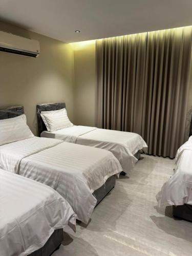 a hotel room with three beds and a window at الشهداء الفاخر للشقق المخدومة in Medina
