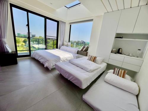 two beds and a couch in a room with large windows at 有風別院民宿 登記編號3098 in Dongshan