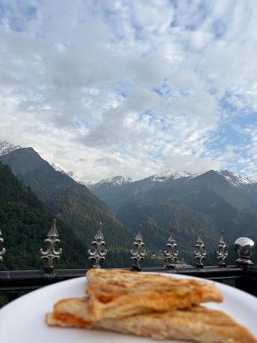 a plate of food on a table with mountains in the background at Sunset Inn tosh in Tosh