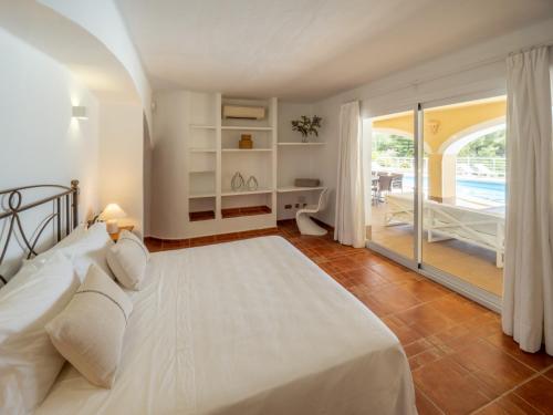 a bedroom with a white bed and a balcony at Ses Casetes Abajo in San Jose