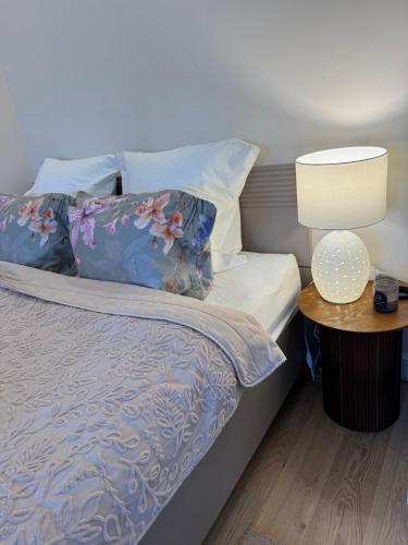 a bed with two pillows and a table with a lamp at Sunny Central Apartment on Central Square in Daugavpils