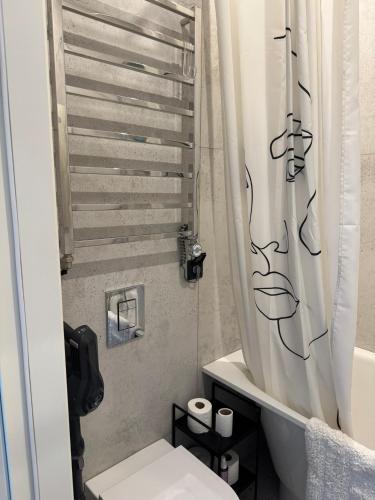 a bathroom with a toilet and a shower curtain at Sunny Central Apartment on Central Square in Daugavpils