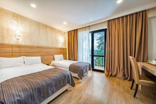 a hotel room with two beds and a desk at BM Plaza in Bakuriani