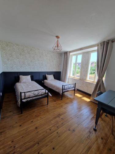 a bedroom with two beds and a window at Les Murmures Desbordes in Châteauvillain