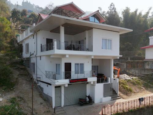 a white house with a balcony on a hill at Magpie Residency Kalimpong in Kalimpong