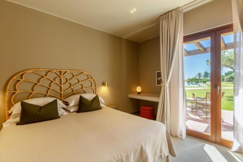 a bedroom with a bed and a large window at Is Molas Resort in Pula