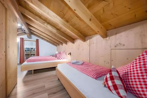 two beds in a room with wooden ceilings at Birkenhof in Sluderno