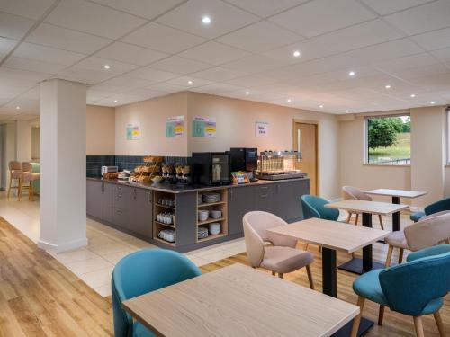 a waiting room with tables and chairs and a counter at Garner Hotel Wolverhampton by IHG in Wolverhampton