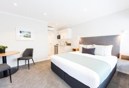 a bedroom with a large bed and a table at Beechwood Boutique Accommodation in Dunedin