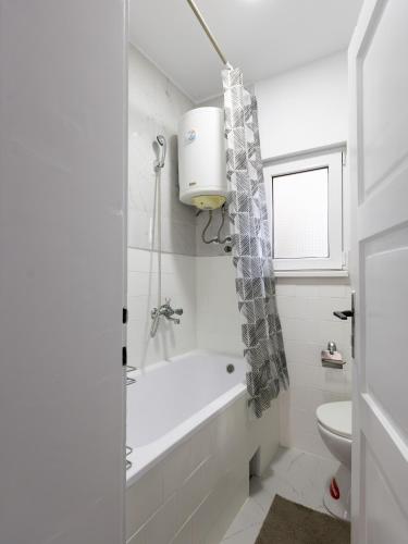 a white bathroom with a tub and a toilet at Apartman Mila Raška in Raška