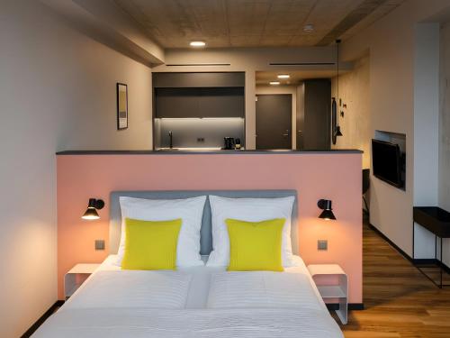 a bedroom with a bed with two yellow pillows at ipartment Leverkusen @HOME by Best Western in Leverkusen