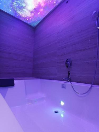 a bathroom with a bath tub with a purple ceiling at hotel sunfire in Chhindwāra